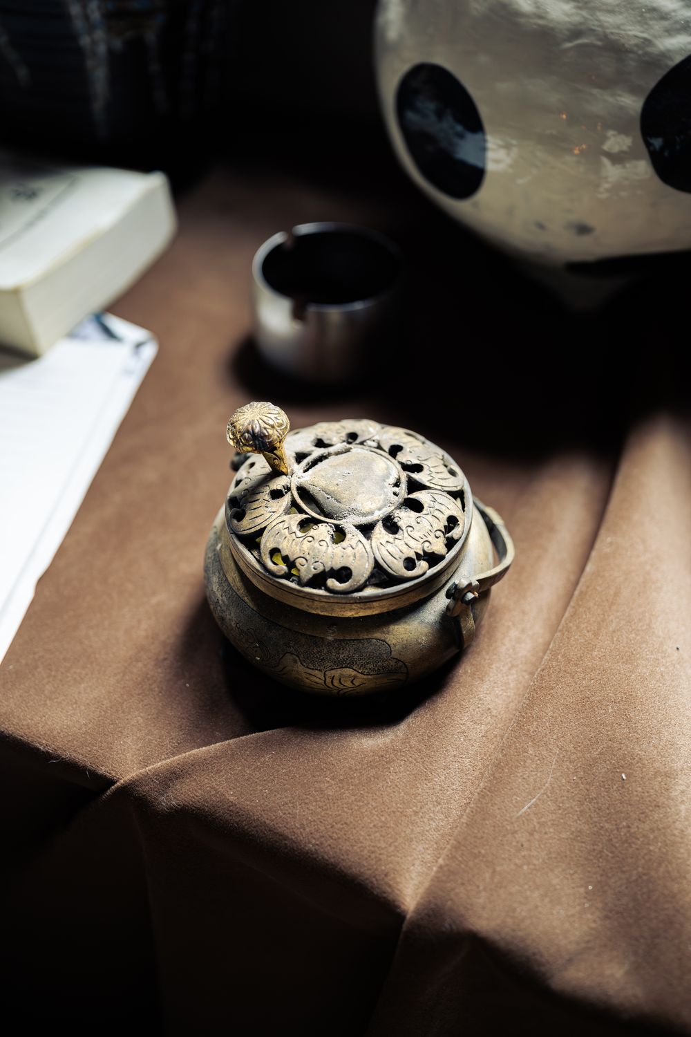 Close-up of an antique incense burner on brown cloth, shallow depth of field