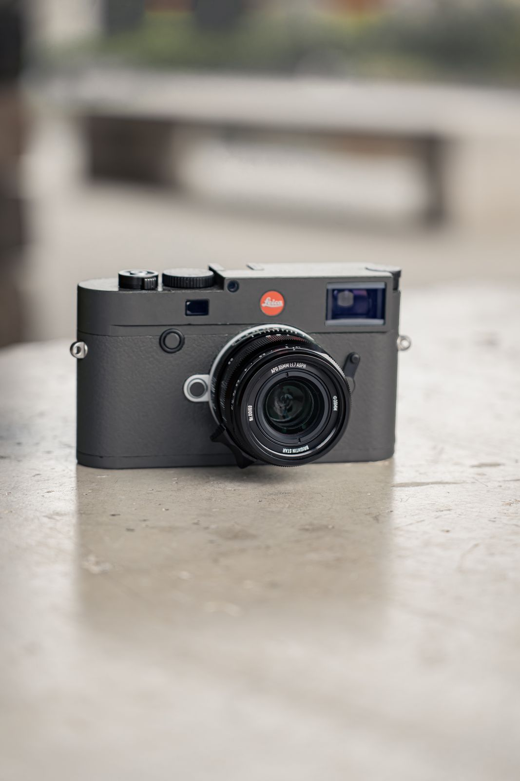 The APO M 35mm mounted on a rangefinder camera, standing on a stone ledge in daylight