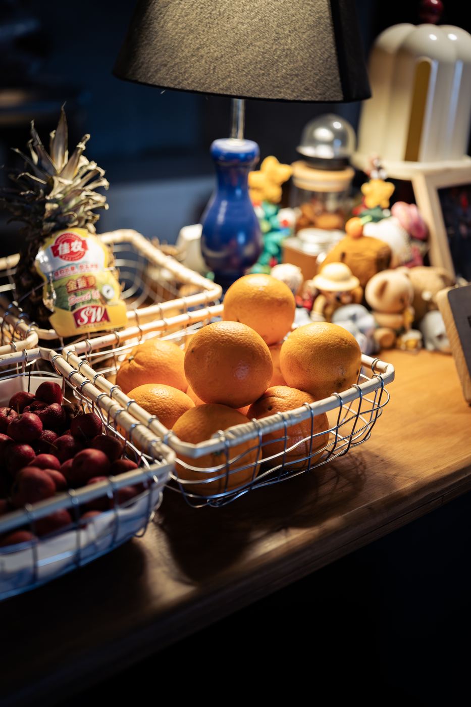 Baskets of oranges and red hawthorn berries in warm lamplight