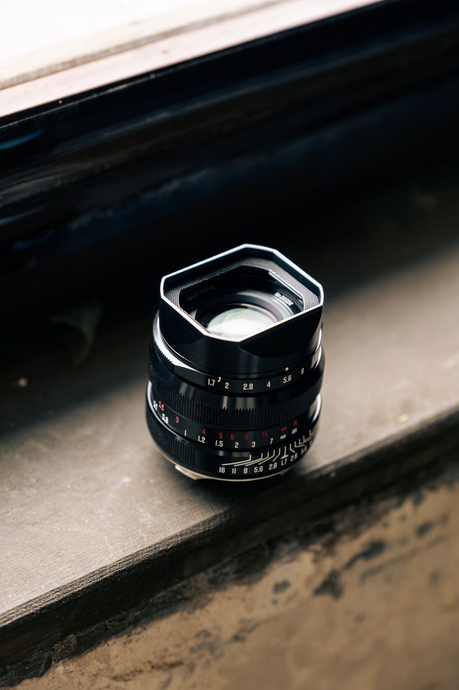 APO M 35mm lens with its square metal hood attached, resting on a stone windowsill