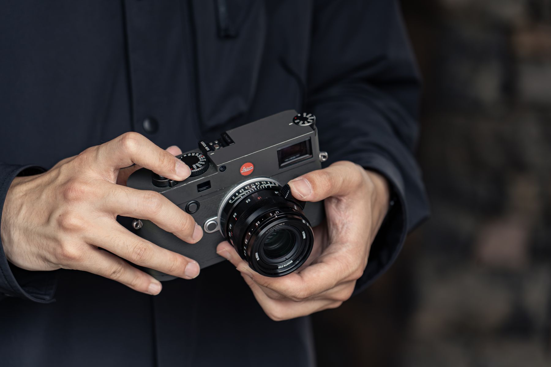 Photographer holding an M-mount rangefinder camera with the APO M 35mm lens attached